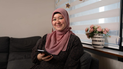 Sevil sidder i sin sofa med mobiltelefonen